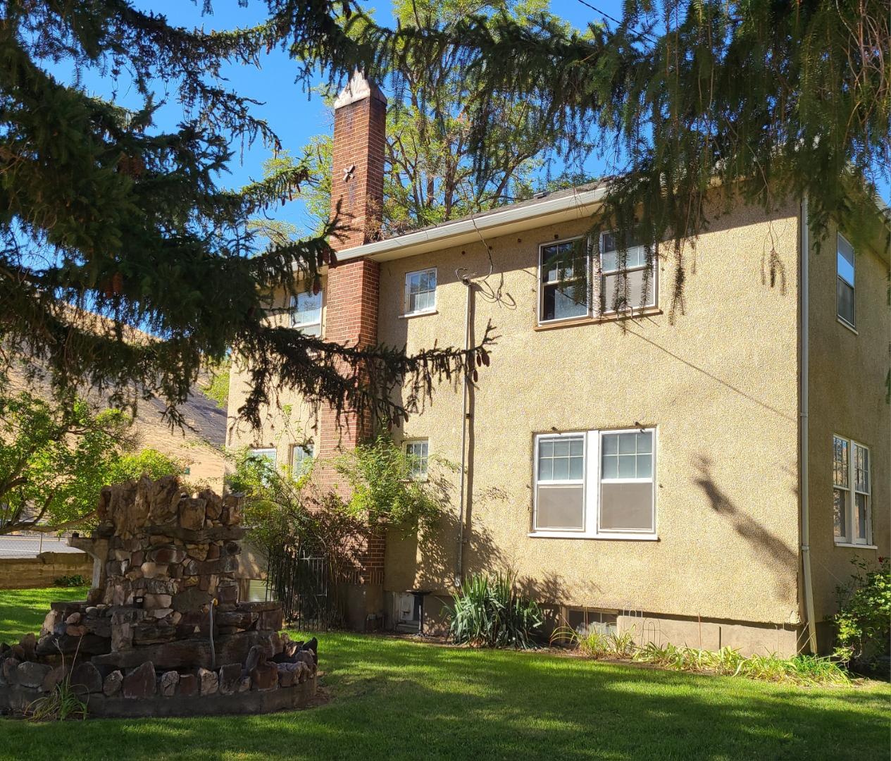 house in yard exterior view of the home and lawn with stone grotto fountain